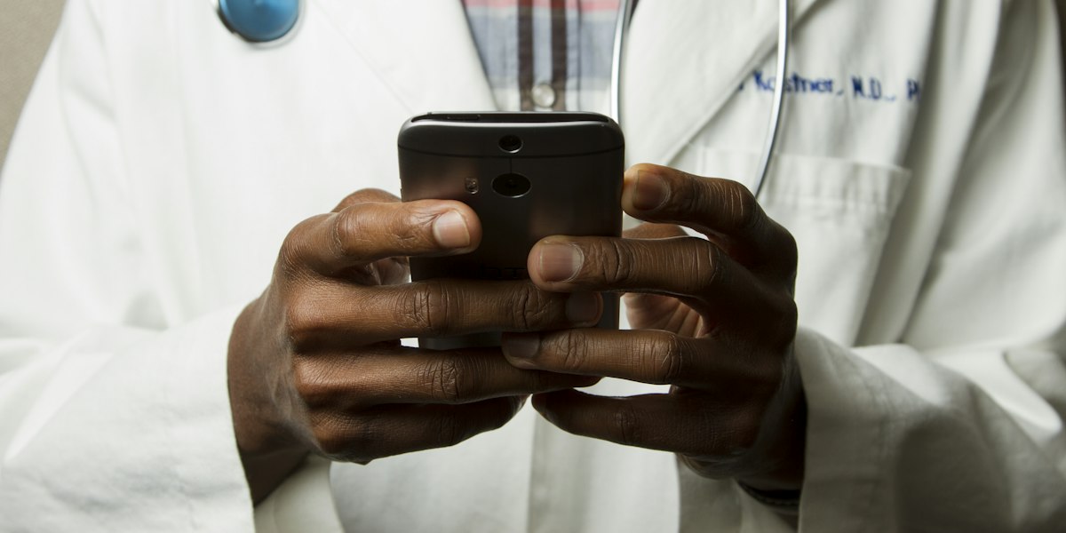 Doctor in a white coat using a smartphone