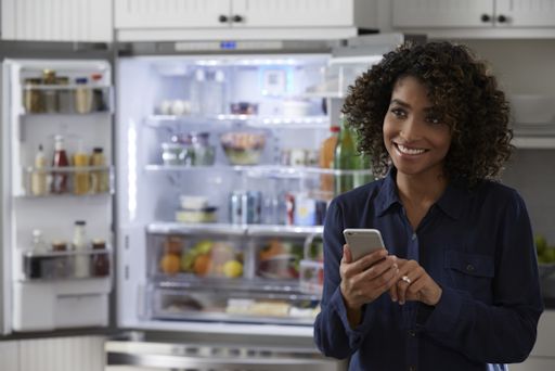 Woman using the Kenmore Smart app at her refrigerator